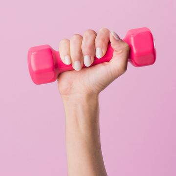 cropped shot of woman holding dumbbell isolated on pink
