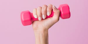 cropped shot of woman holding dumbbell isolated on pink