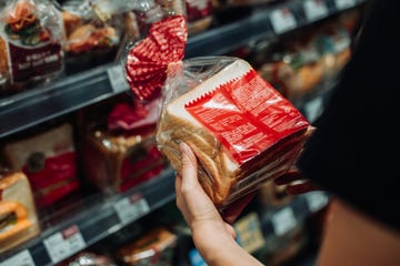 cropped shot of young asian woman grocery shopping in supermarket, shopping for fresh bakery and reading the nutrition label at the back of a packaged bread routine shopping healthy eating lifestyle