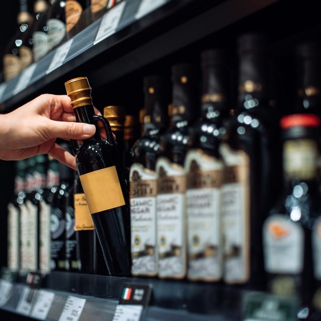 cropped shot of young woman grocery shopping in supermarket, picking up a bottle of vinegar from the product aisle. routine shopping. making a healthier food choice. healthy eating lifestyle