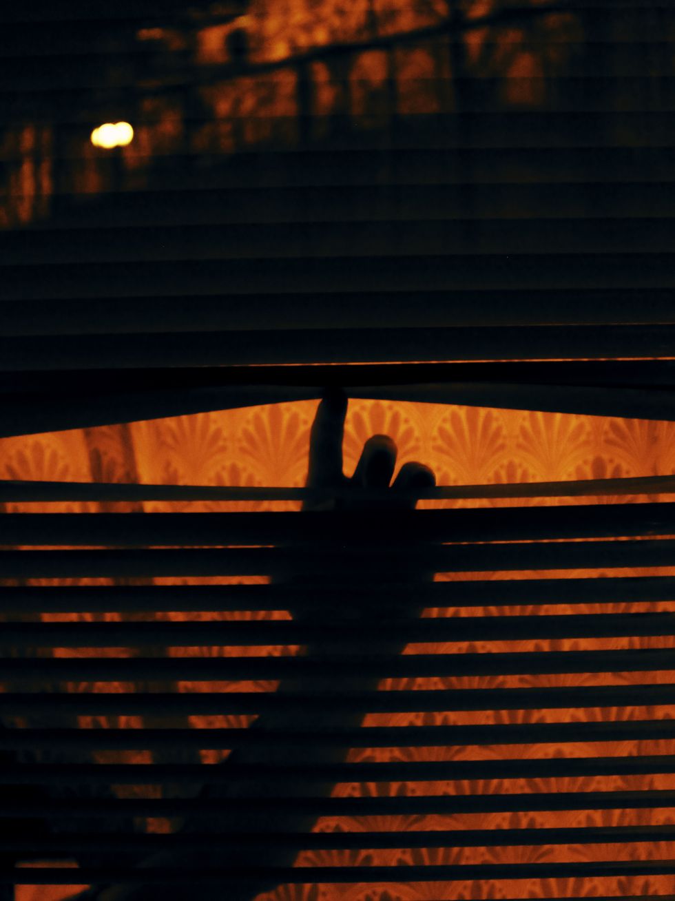 cropped silhouette hand on blinds at home