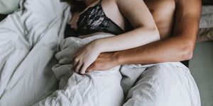 Cropped view of couple spooning in bed