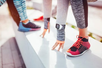Cropped view of female runners warming up in city