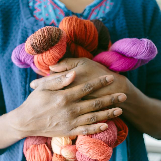 cropped view of woman clutching colorful yarn