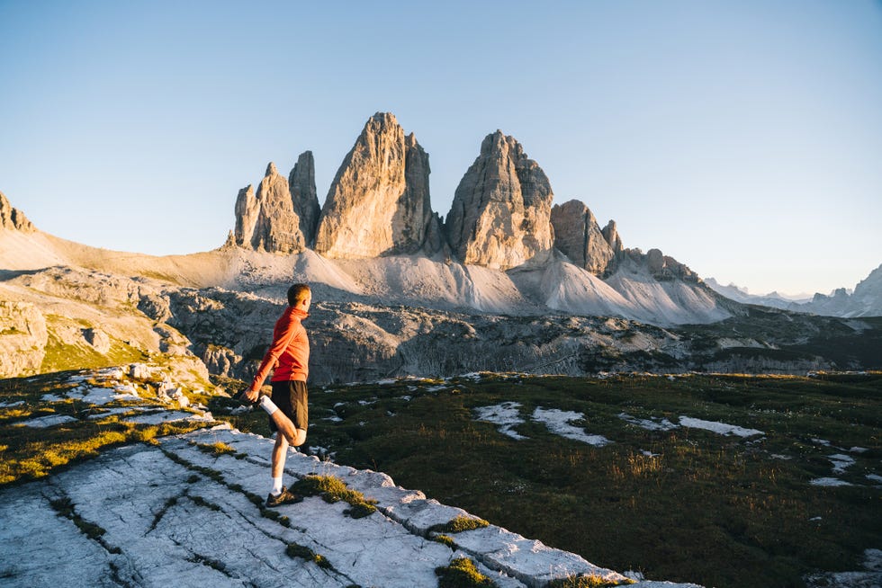 cross country runner stretches on a high mountain meadow at dawn