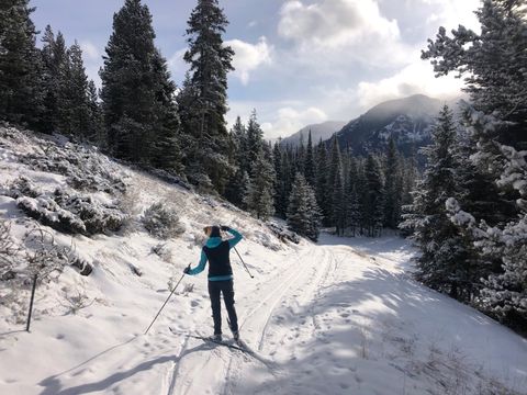 woman looking at mountains while cross country skiing on snowy trail