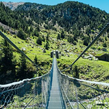 crossing a tibetan suspension bridge during summer hike in the andorra pyrenees.