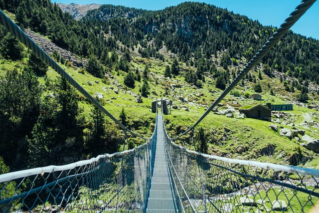 crossing a tibetan suspension bridge during summer hike in the andorra pyrenees.
