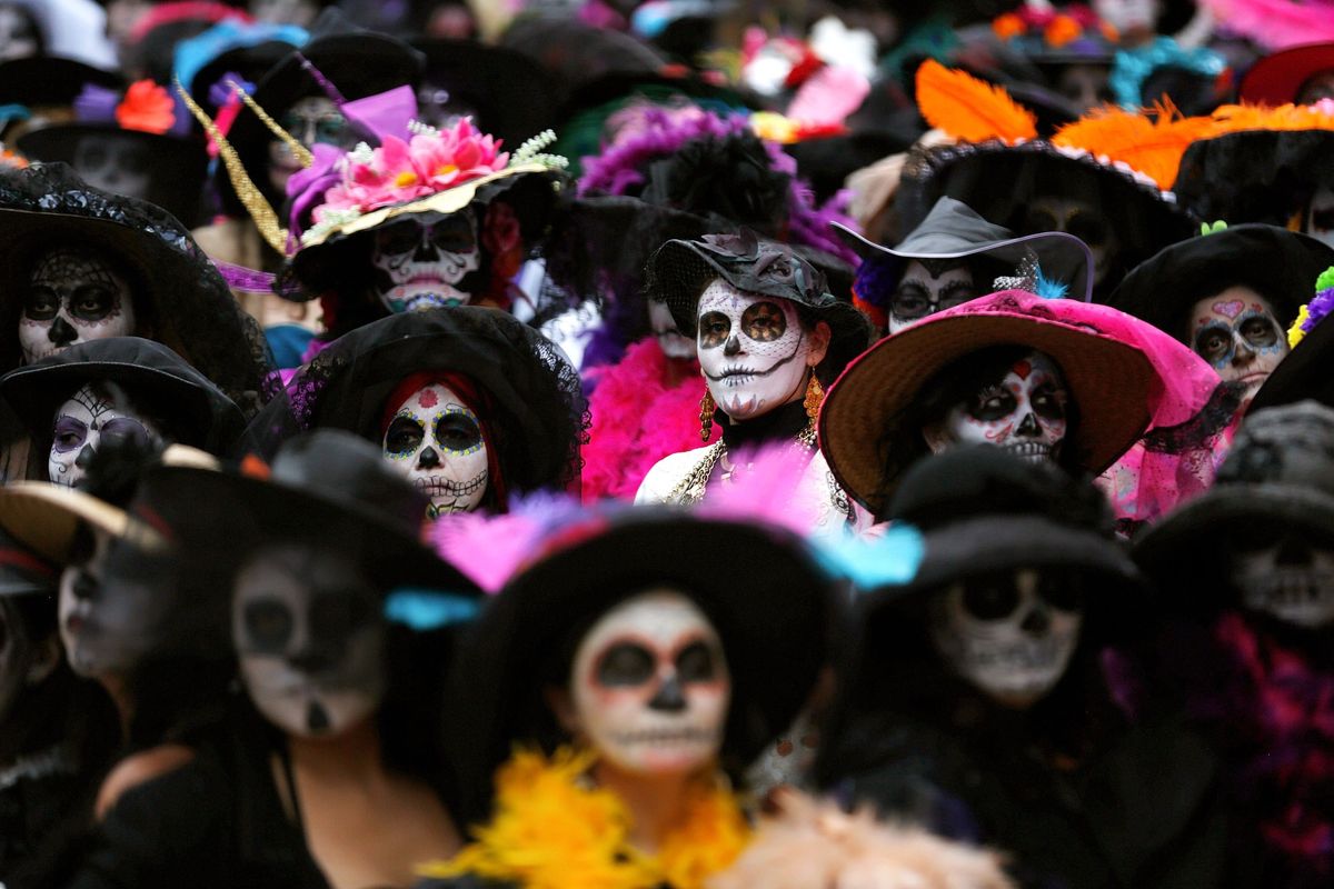 Mensen vieren Da de los Muertos in MexicoStad door zich uit te dossen als een bekend feestsymbool een figuur van een skelet dat calaveraCatrina wordt genoemd