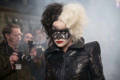 emma stone as cruella de vil with a half black, half white wig, black leather jacket, with the future stenciled in black across her face