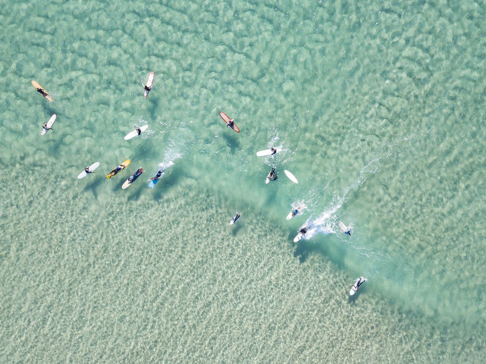 crystal clear waters with surfers seen from above