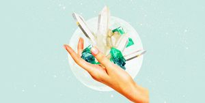 a hand holds up a fistful of green and white crystals over a pale green backghround