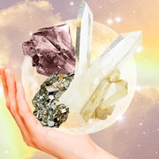 Taurus Crystals a hand holds up a variety of crystals in front of a full moon and a rainbow sky