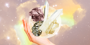 a hand holds up a variety of crystals in front of a full moon and a rainbow sky