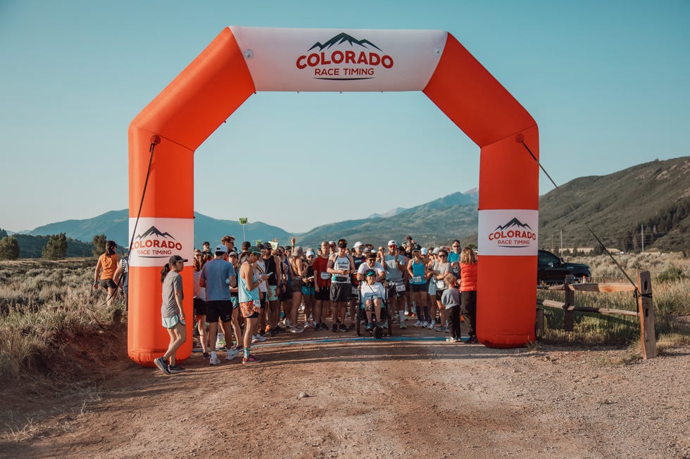 participants gathered at the starting line of a running event under an inflatable arch aspen valley marathon half aspen valley marathon