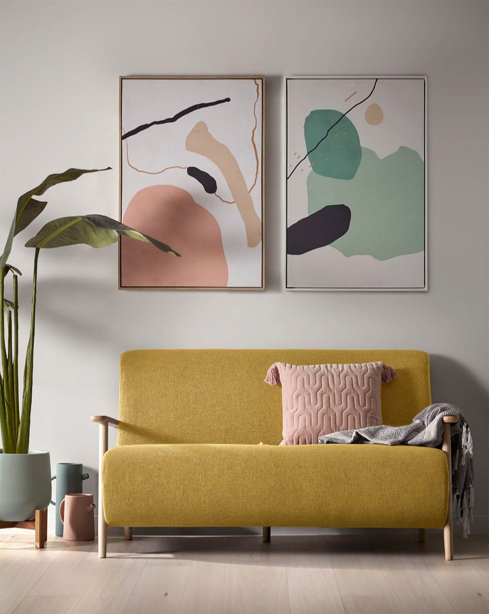 salón con sofá mostaza y dos cuadros de arte abstracto en la pared