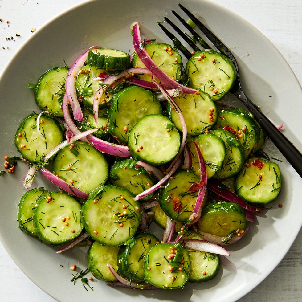 cucumber salad with red onions, mustard seeds, with a fork in a bowl