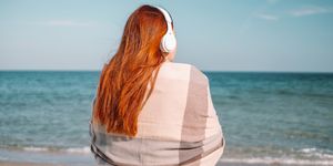 donna che ascolta la musica al mare con cuffie bluetooth