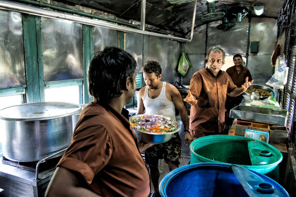 De staf van de keukenwagon van de Mandovi Express werkt in de bloedhitte geen airco aan de lunch voor de passagiers onderweg naar Goa