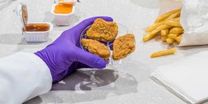 Cultured chicken nuggets on a petri dish with a purple glove
