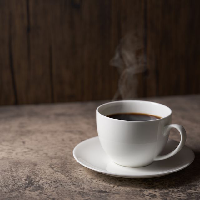cup of coffee with grains on wooden background