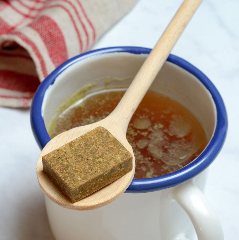 cup with bouillon broth and bouillon cubes on a wooden spoon, germany
