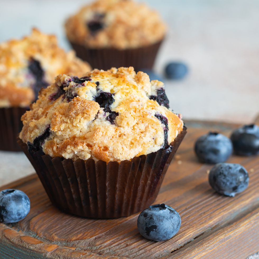 cupcakes (muffins) with blueberries and streusel (confectionery crumbs) on a wooden stand. a delicious summer dessert for morning tea or breakfast.