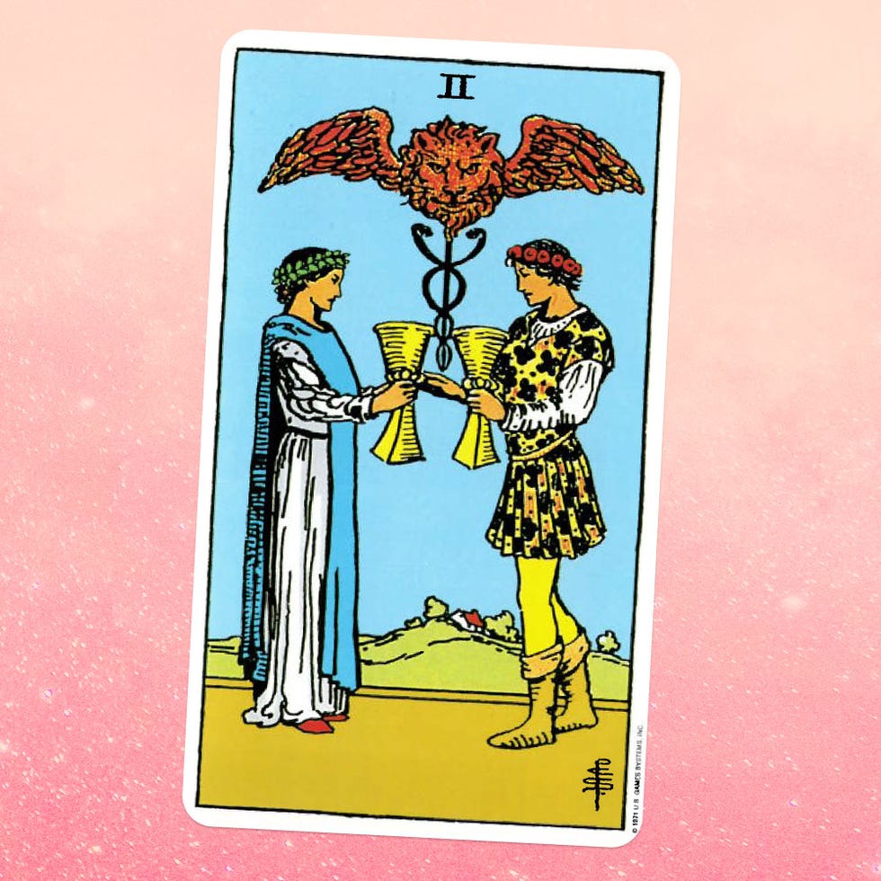 the two of cups tarot card, showing a woman in a white robe and a man in a yellow page outfit facing each other, holding goblets, with a winged lion above them