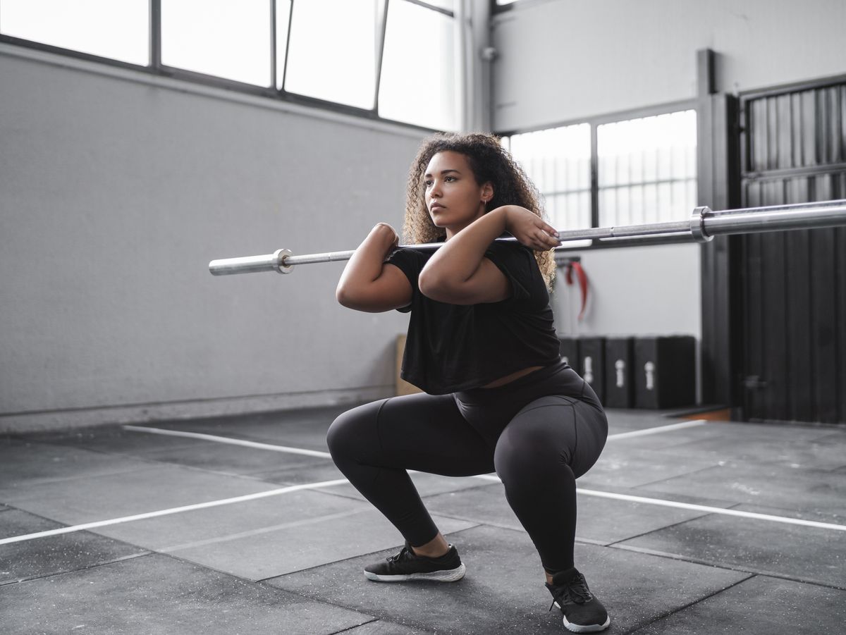 A woman doing a back squat with two dumbbells photo – Working out