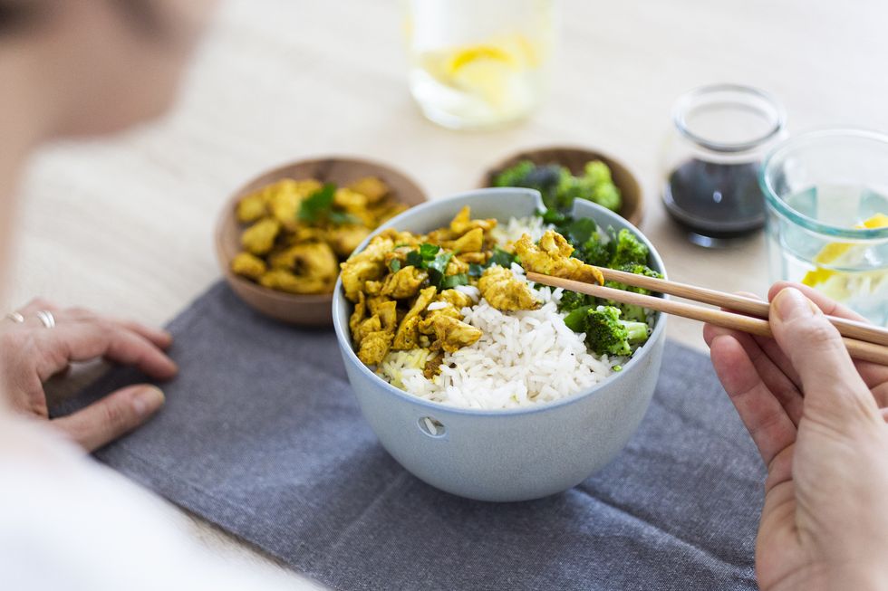 curry chicken, broccoli and rice, woman with chopsticks