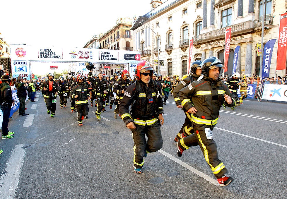 varios bomberos equipados con sus trajes corren en el inicio de la cursa de bombers de barcelona