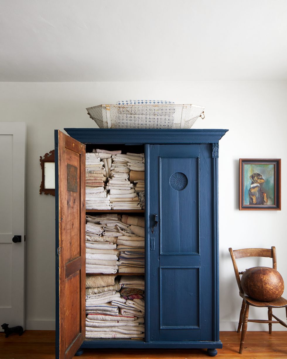 antique blue armoire stacked full with vintage french linens