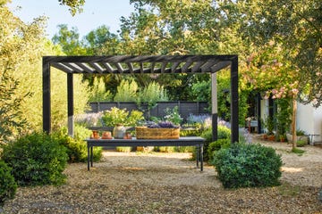 black wood pergola in lavender garden with long table underneath