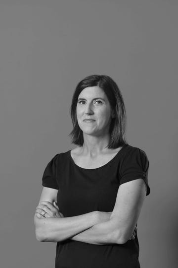 person with arms crossed wearing a black shirt against a gray background