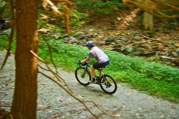 a woman riding a bike on a gravel road