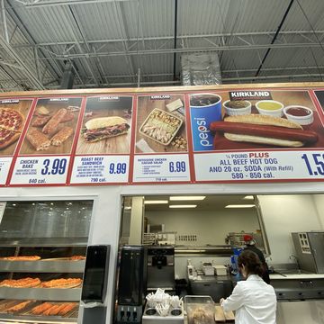 customer at pick up window of costco food court, with picture menu, florida