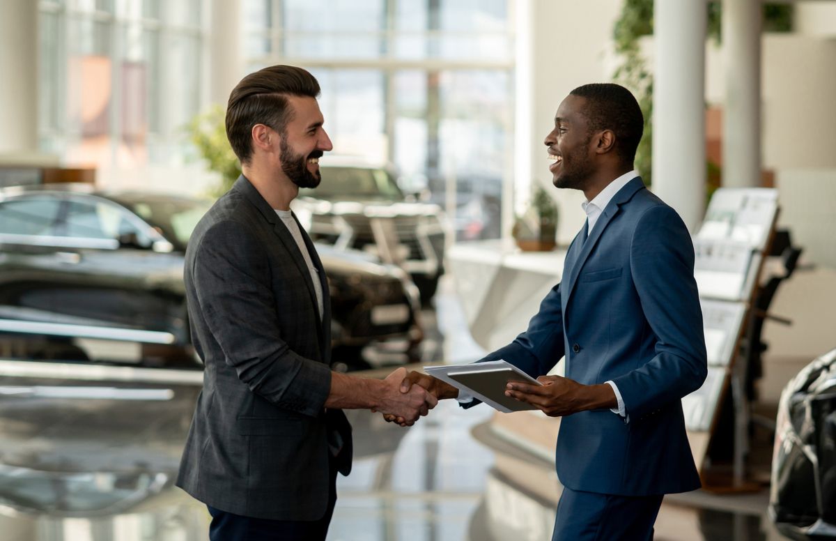 customer closing a deal with a salesman at a car dealership