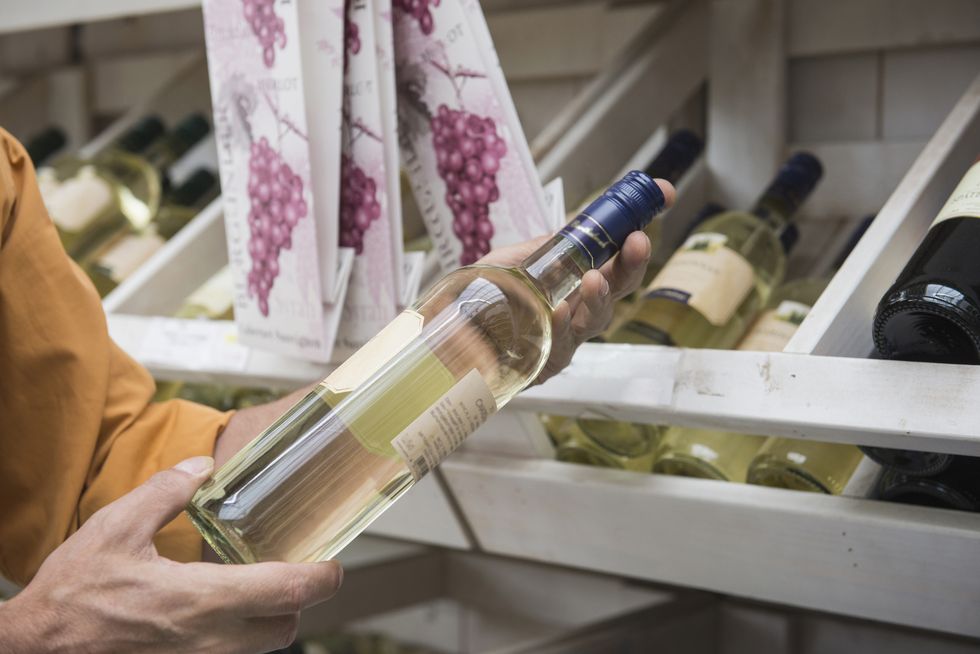 白ワインをスーパーマーケットで選ぶ女性