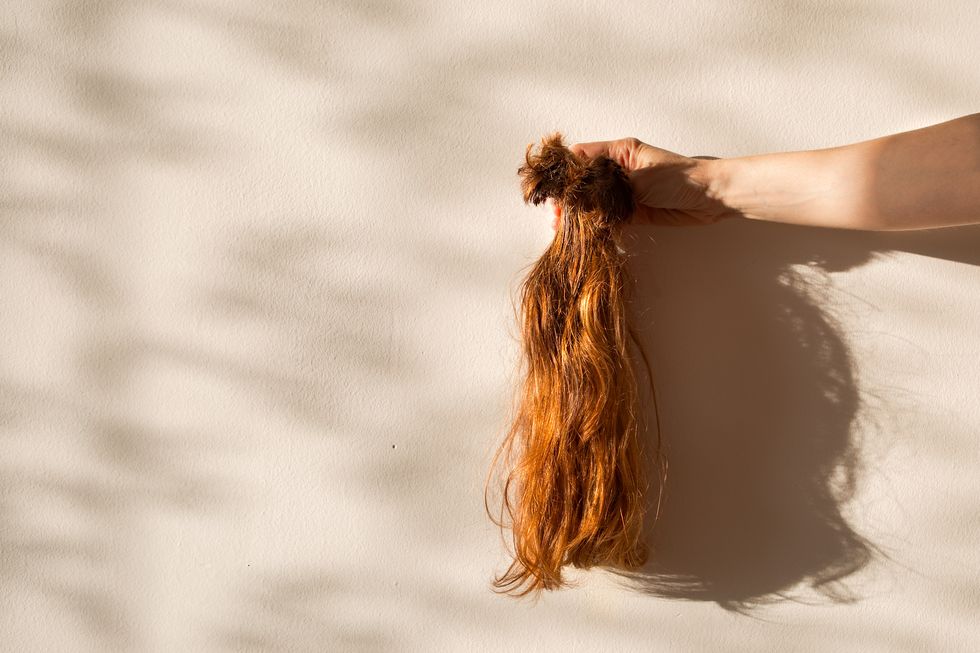 cut off hair, dangling from woman's hand