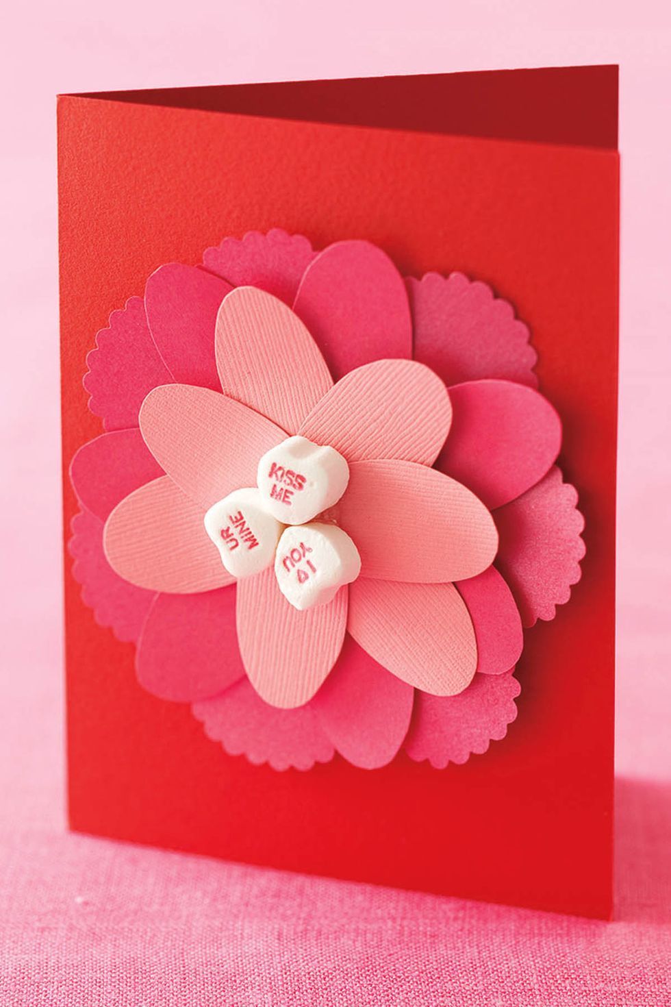 red valentine's day card with pink 3d flower on front made from cut paper petals and candy conversation hearts center