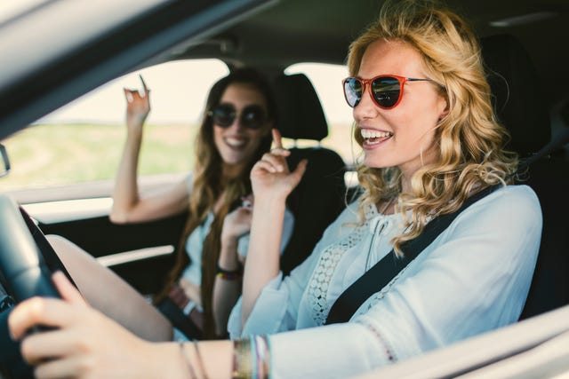 women on the road trip driving in the car, singing and enjoying the journey