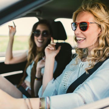 women on the road trip driving in the car, singing and enjoying the journey