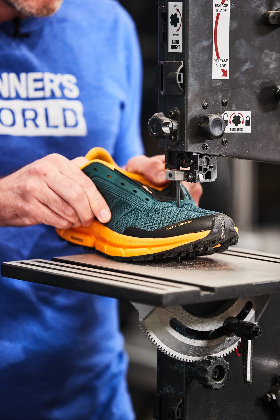 a person is holding a running shoe made of green and yellow materials, positioned on a machine table