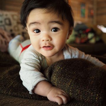 cute five month old baby on sofa staring at camera