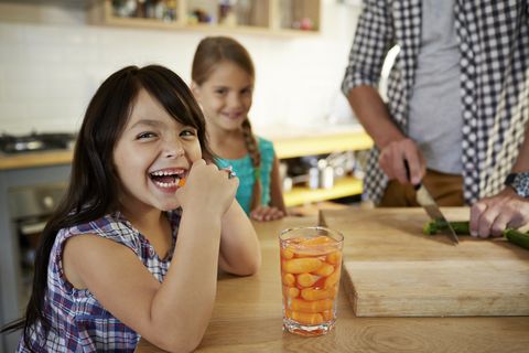 girl eating baby carrots in kitchen