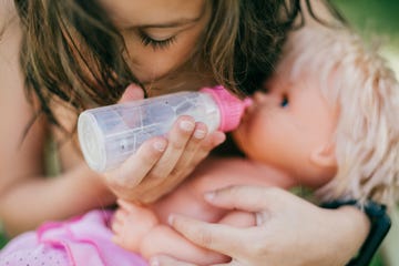 niña con muñeco dándole biberón