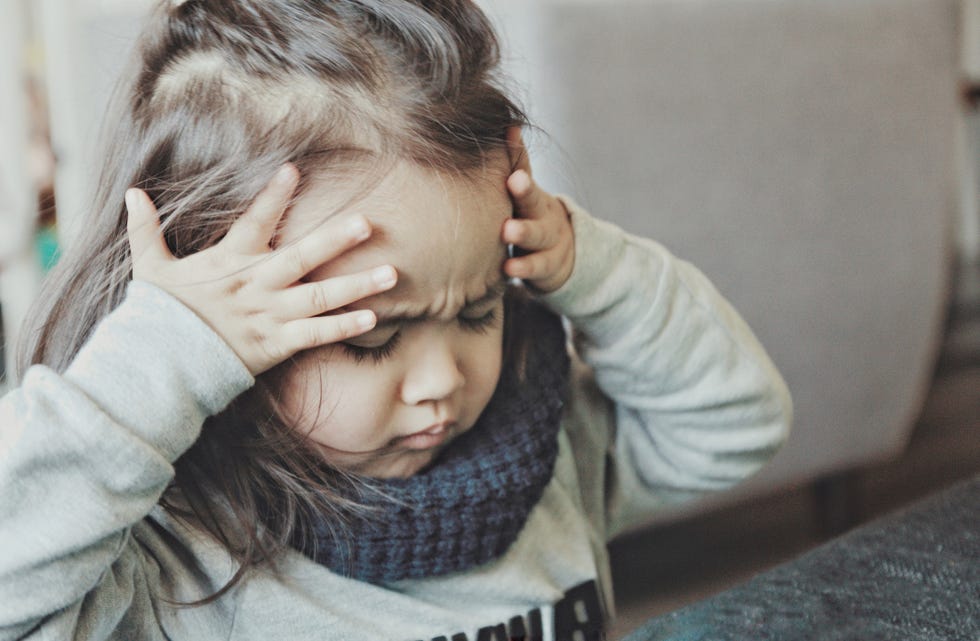 niña tocándose la cabeza con las manos porque le duele