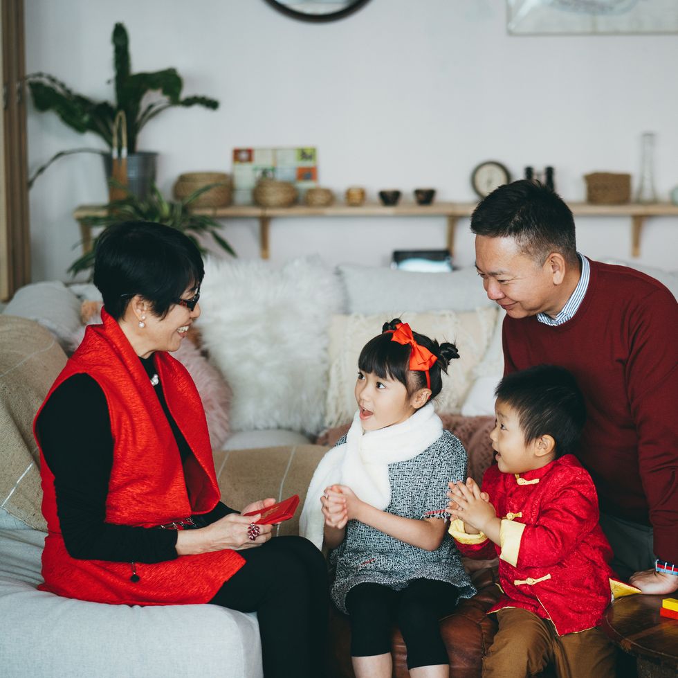 cute little granddaughter and grandson dressed in red traditional chinese costume greeting to grandparents and receives red envelops lai see joyfully in chinese new year