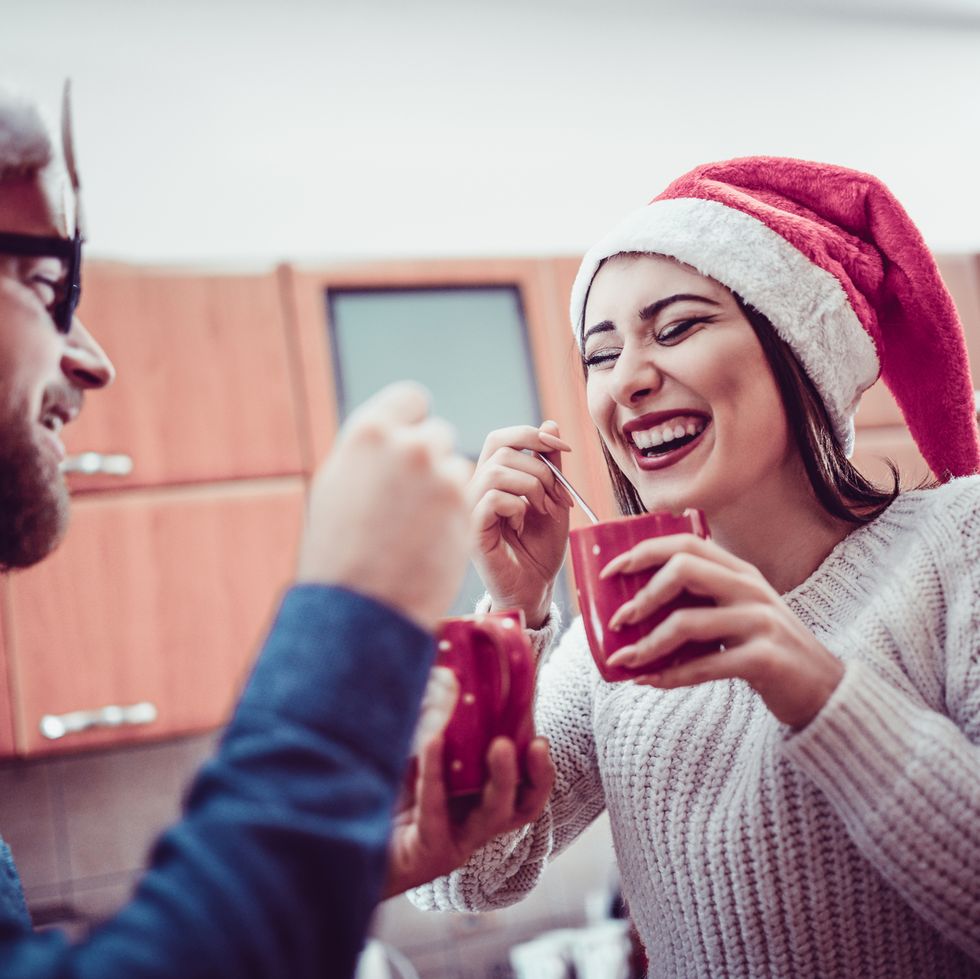 cute smiling couple drinking hot drink at christmas party