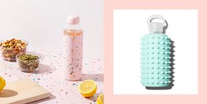 two glass water bottles with silicone grips one is pink with multicolored speckles and the other is blue with spikes